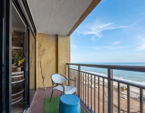 A balcony with a view of the ocean, a chair, a small round table, and a potted plant. - Caravelle 937 (Myrtle Beach)