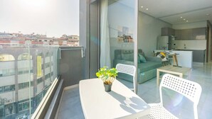 A modern apartment with a balcony, a dining area, and a living room with a sofa and a kitchen in the background. - Faya Nova-central stay (Casablanca)