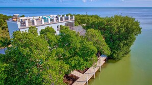 A coastal property with a balcony overlooking the sea, surrounded by lush greenery. - Oceanfront Rooftop Views w/ 75ft of Dockage (Marathon)