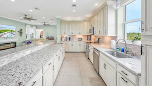 A spacious kitchen with white cabinetry, granite countertops, and a large island. - Oceanfront Rooftop Views w/ 75ft of Dockage (Marathon)