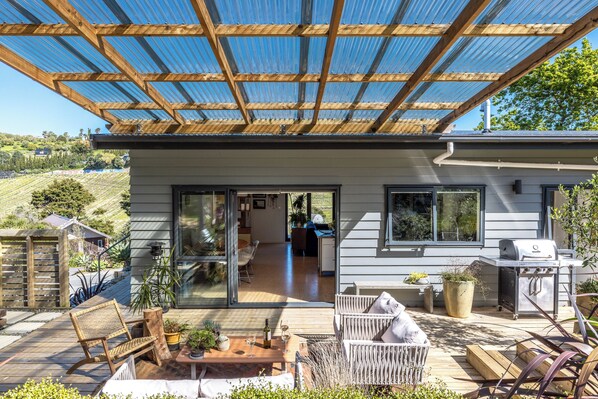 Una casa moderna con patio coperto, porte scorrevoli in vetro e zona barbecue.