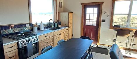 A kitchen with a large island, wooden cabinets, and a dining area with a table and chairs.