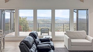 Un salon spacieux doté d’une grande fenêtre offrant une vue panoramique sur les montagnes.