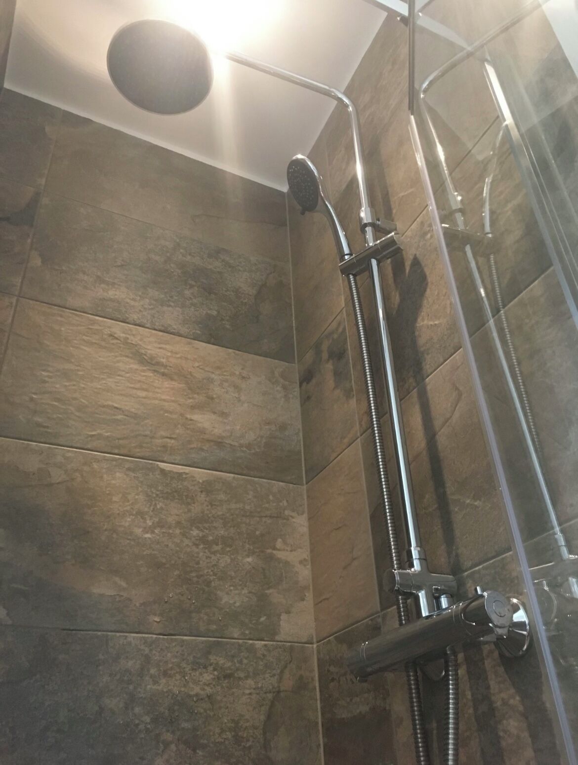 A shower with a handheld showerhead and a wall-mounted faucet.