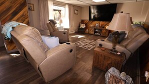 A modern living room with leather recliners, a flat-screen TV, and a wooden coffee table.