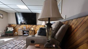 A cozy living room with a sofa, a lamp, a TV, and a wooden sideboard.