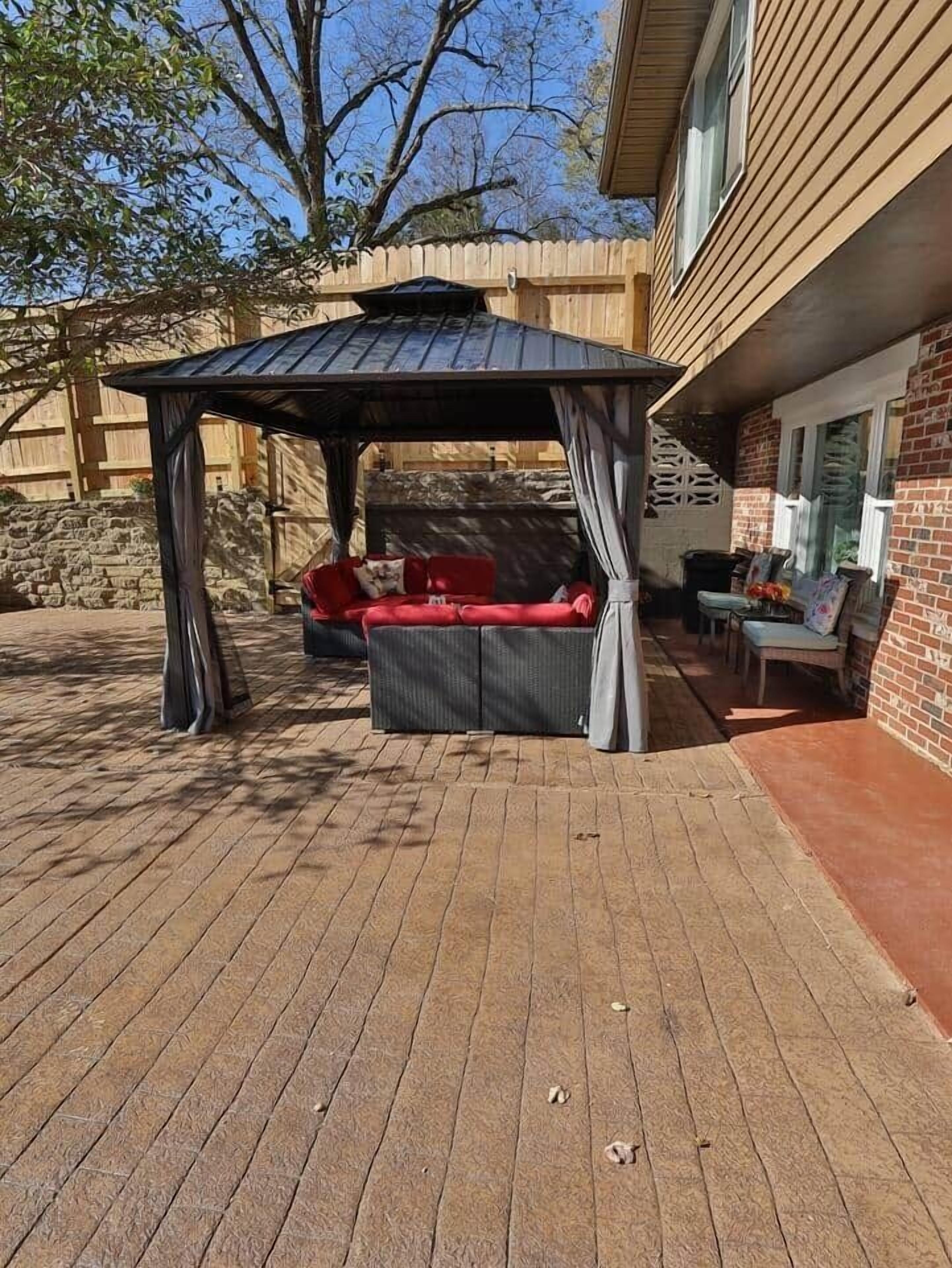 Un patio cubierto con un conjunto de asientos acolchados y una estructura de pérgola.