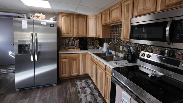 A modern kitchen with stainless steel appliances, wooden cabinets, and a patterned backsplash.