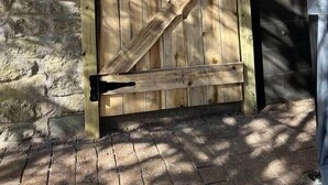 A wooden gate with a cross design, set against a stone wall and wooden fence.
