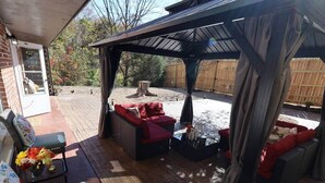 An outdoor patio area with wicker furniture, a fire pit, and a covered seating area.