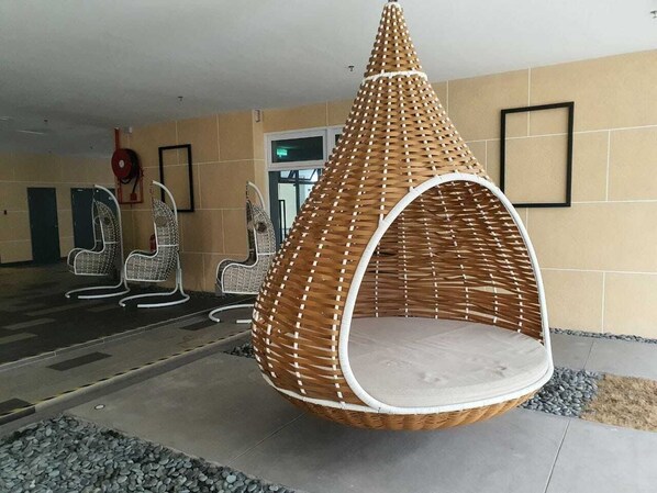 Een hangstoel met een geweven patroon en een bekleed zitje, in een interieur.