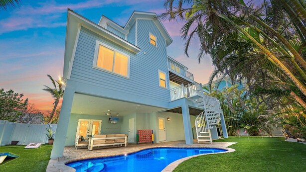 Ein zweistöckiges Haus mit Swimmingpool, überdachter Terrasse und Wendeltreppe.