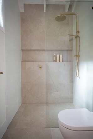 A modern bathroom with a glass-enclosed shower, a toilet, and a shelf with toiletries. - Romantic Guest House with Mountain Views (Witheren)