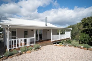 A white two-story house with a covered porch, a chimney, and a gravel driveway with rocks and plants. - Romantic Guest House with Mountain Views (Witheren)