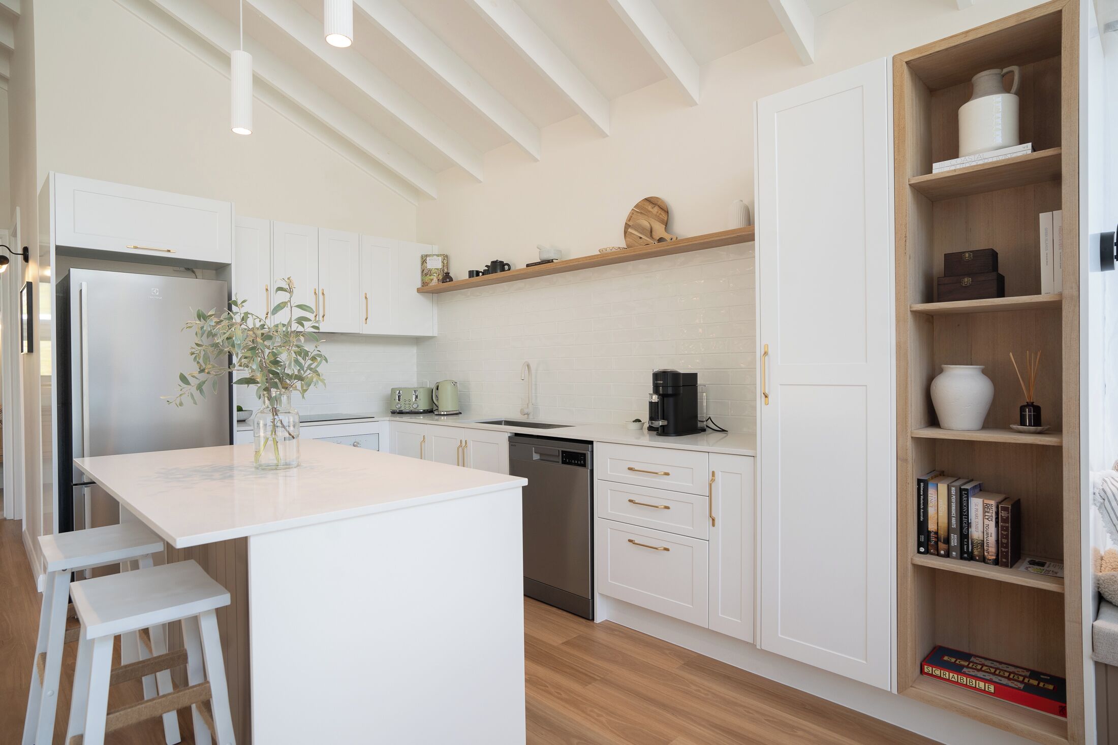 Une cuisine moderne avec des meubles blancs, un îlot central et une bibliothèque intégrée.