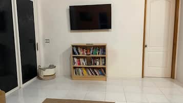 Una habitación con puerta corredera de vidrio, una estantería, un televisor montado en la pared y una puerta cerrada.