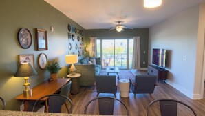 A living room with a sofa, chairs, a dining table, and a TV. - Retro 1 Bedroom, King Bed, Large Living Area, Parking, Gym, Close to UAB (Birmingham)