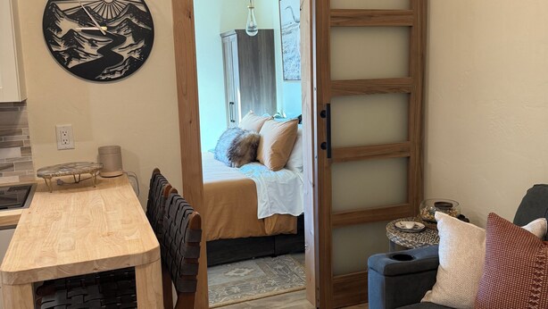 Un salon moderne avec une table à manger en bois, un canapé et une porte coulissante donnant sur une chambre.