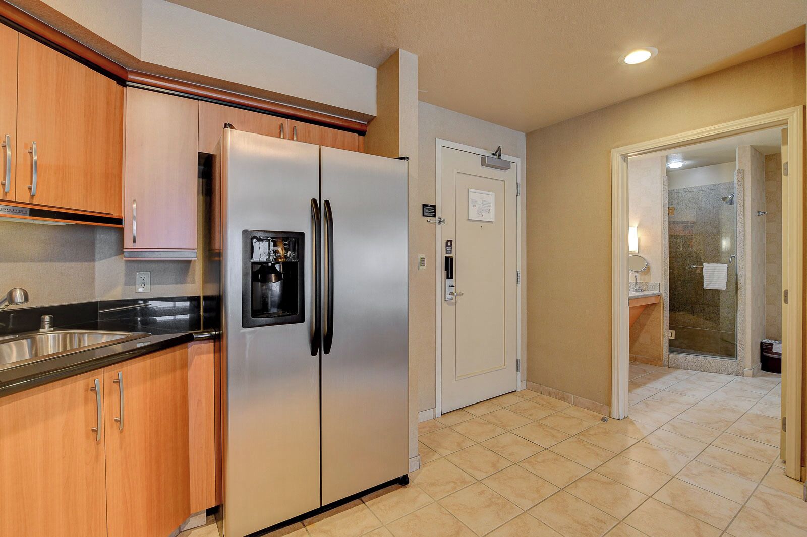 A kitchen with a stainless steel refrigerator, wooden cabinets, and a built-in water dispenser.