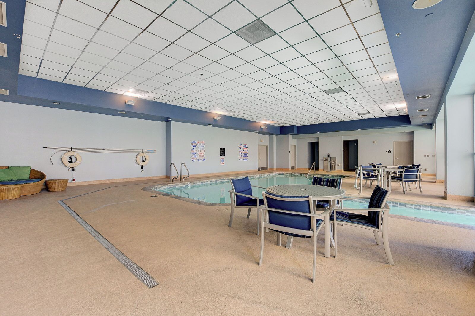 A swimming pool area with a pool table, lounge chairs, and safety equipment.
