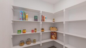 Ett vitt inredningsalternativ med hyllor som innehåller olika livsmedel och några böcker.
