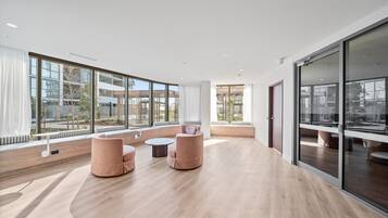 A spacious room with large windows, a wooden floor, and a seating area with two sofas and a small table.