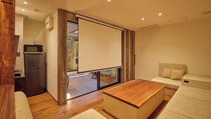 Un soggiorno moderno con un tavolino in legno, un divano e una zona cucina con frigorifero.