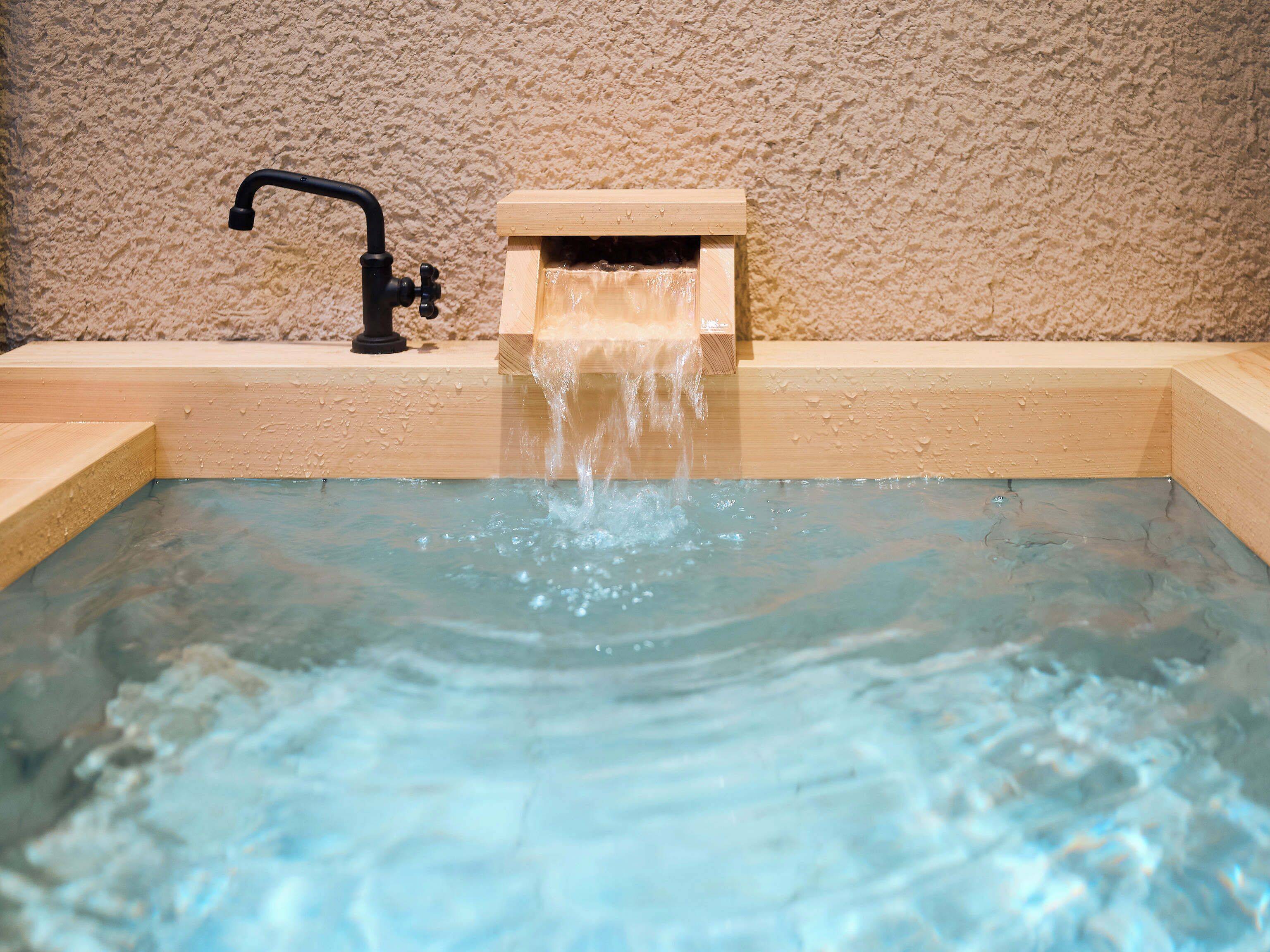 A small wooden bathtub with a faucet and a wooden box, likely for storing bath items.