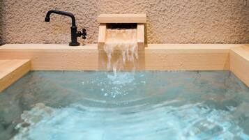 A small wooden bathtub with a faucet and a wooden box, likely for storing bath items.