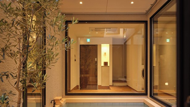 Un'area spa moderna con un solarium in legno, una vasca idromassaggio in vetro e una pianta in vaso.