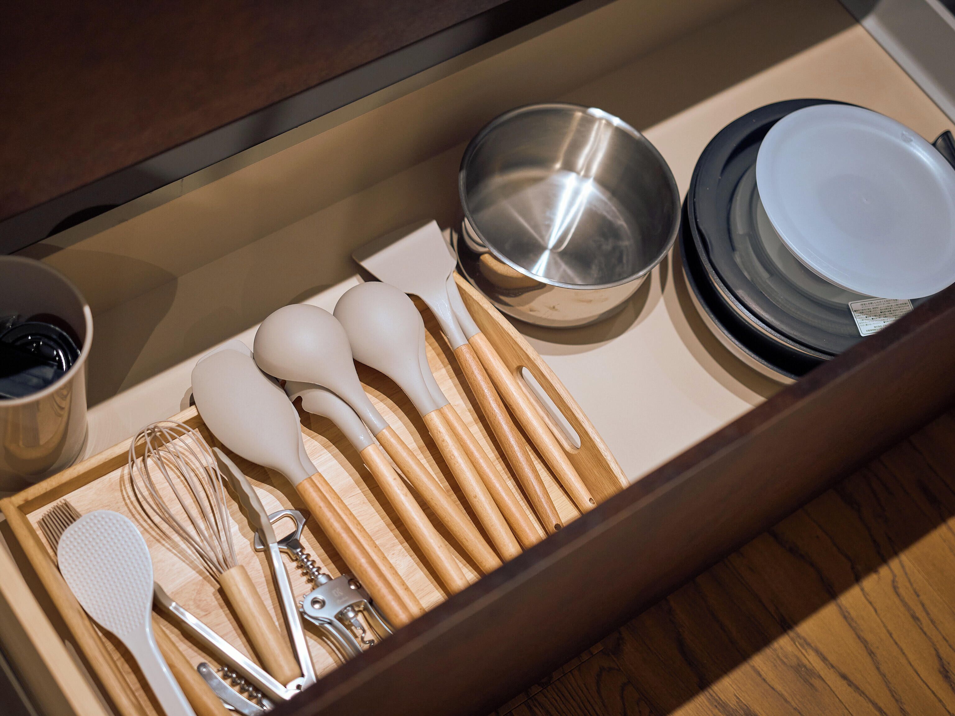 A drawer containing kitchen utensils including whisks, spatulas, and a bottle opener.