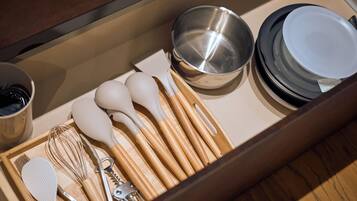 A drawer containing kitchen utensils including whisks, spatulas, and a bottle opener.