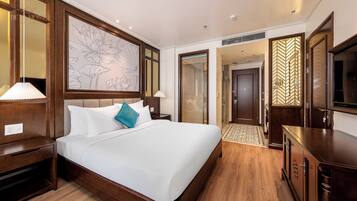 A hotel room with a large bed, wooden headboard, a wall-mounted artwork, a television, and a wardrobe.
