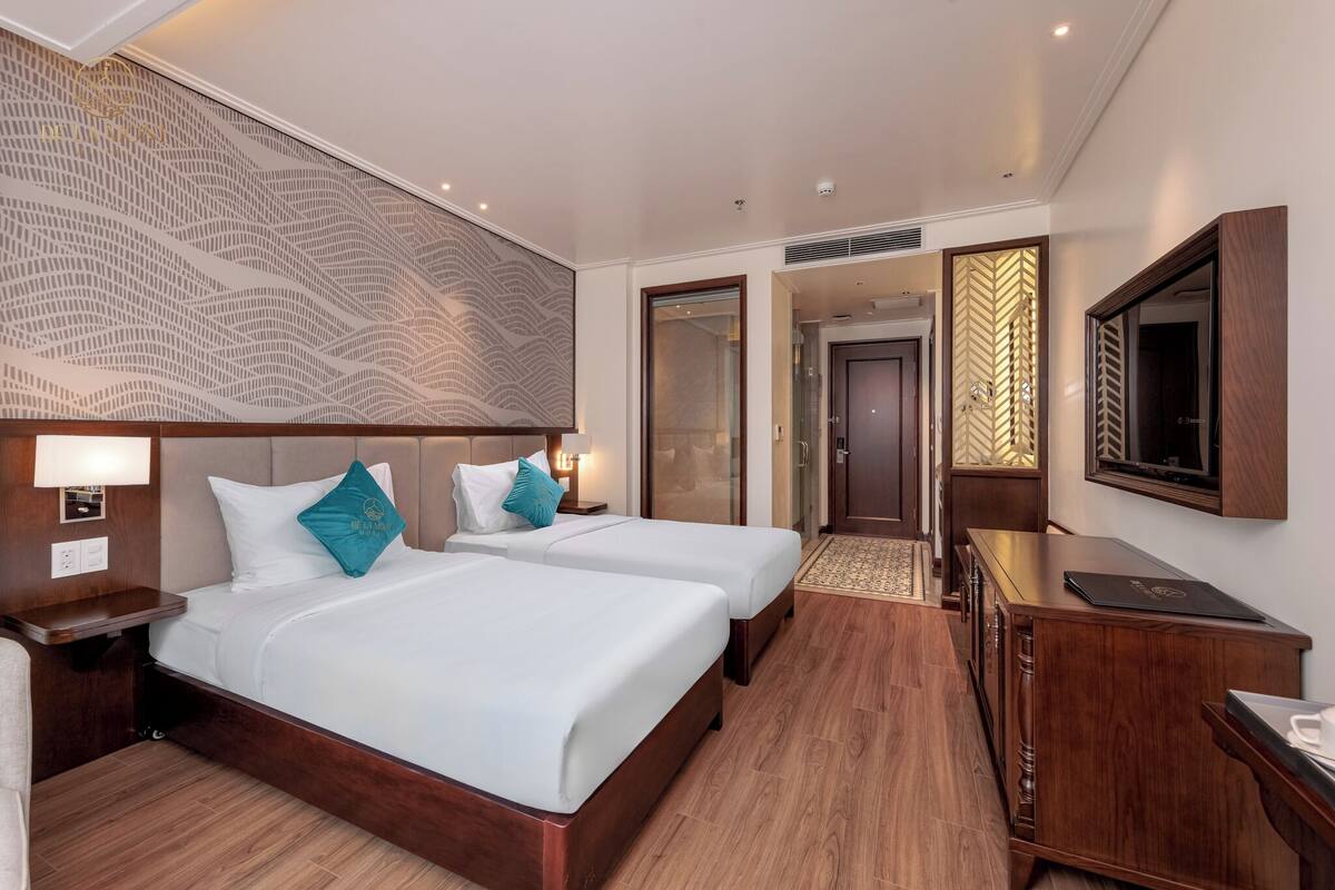 Une chambre d’hôtel avec deux lits, un bureau, une télévision et un panneau décoratif mural.