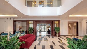 Eine geräumige Lobby mit Schachbrettmuster-Boden, einem roten Sofa und Topfpflanzen.