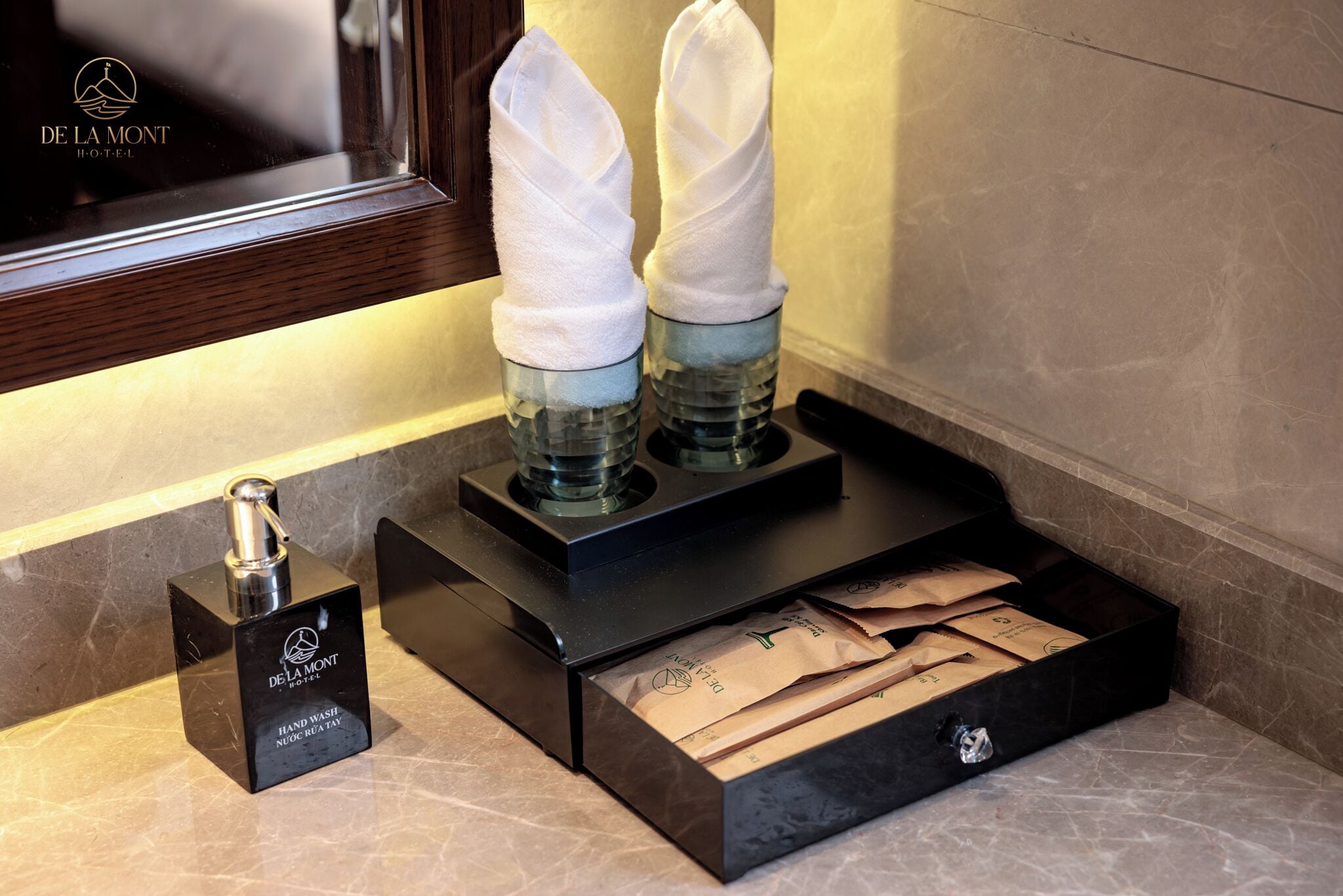 A hand wash station with a bottle of hand soap and towels at De La Mont Hotel.
