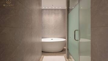 Un baño moderno con una bañera independiente, un box de ducha de vidrio y suelo de mármol.