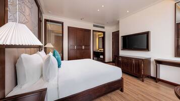 Una habitación de hotel con una cama grande, un armario de madera, televisión y escritorio.