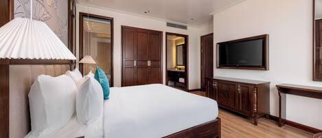 Una habitación de hotel con una cama grande, un armario de madera, televisión y escritorio.