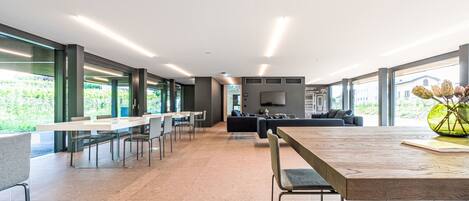 A modern office space with a long table, chairs, a sofa, and a TV.