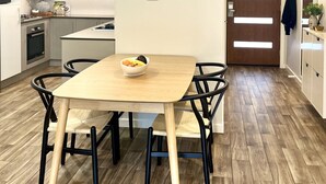 A modern kitchen with a dining table, chairs, a clock, and a wooden floor. - Stylish Townhouse With Private Courtyard (Canberra)