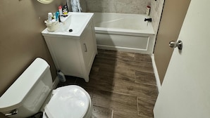 Een kleine badkamer met toilet, wastafel en bad.