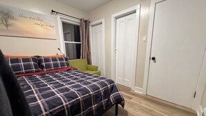 Een slaapkamer met een bed, een raam, een deur en een muur met een poster.