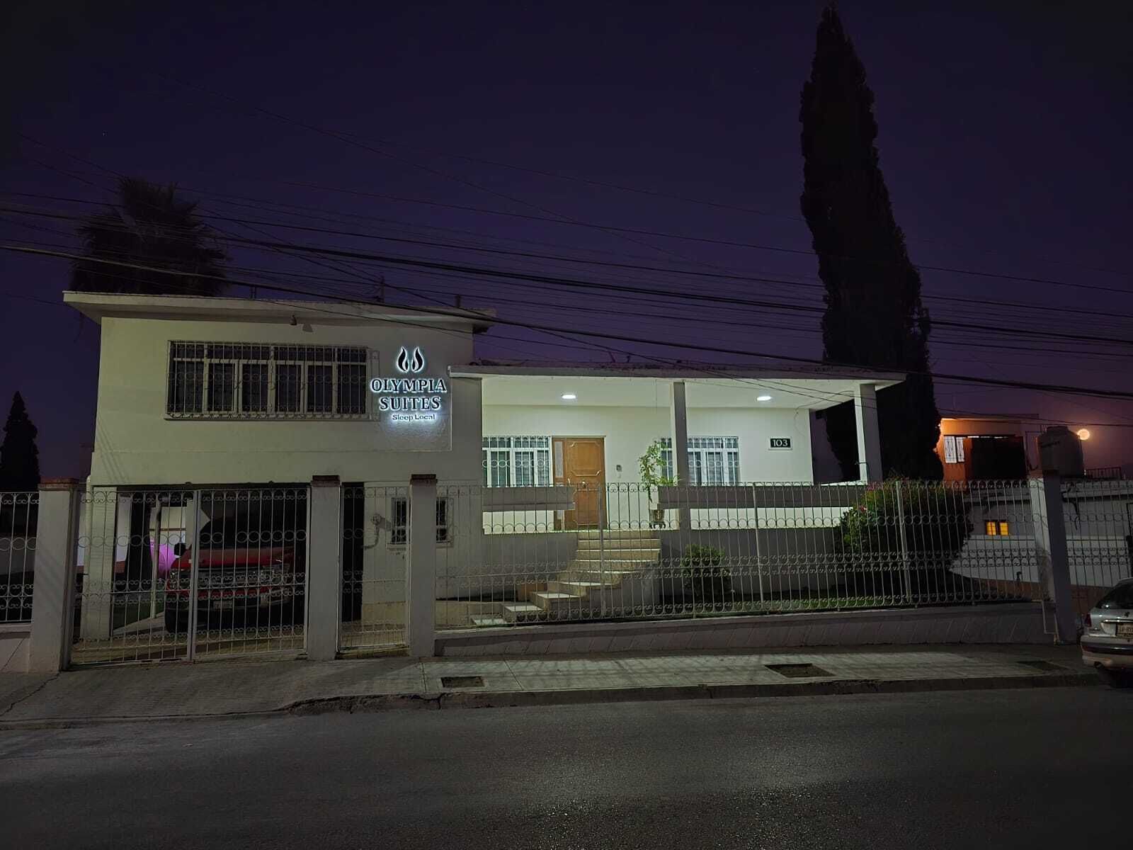 Un edificio de dos pisos con un letrero que dice "Olympia Suites Sleep Local".