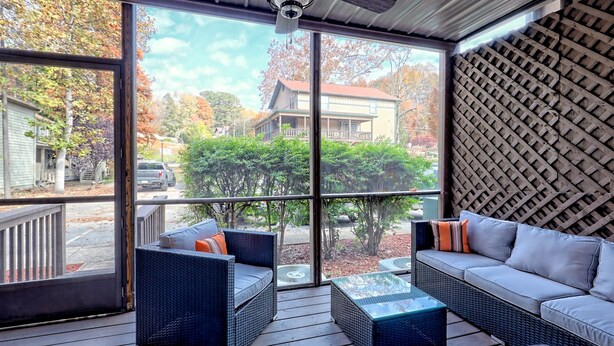 A covered porch with wicker furniture, large windows, and a lattice wall. - Downtown Helen - 1st Floor | Free Parking (Helen)