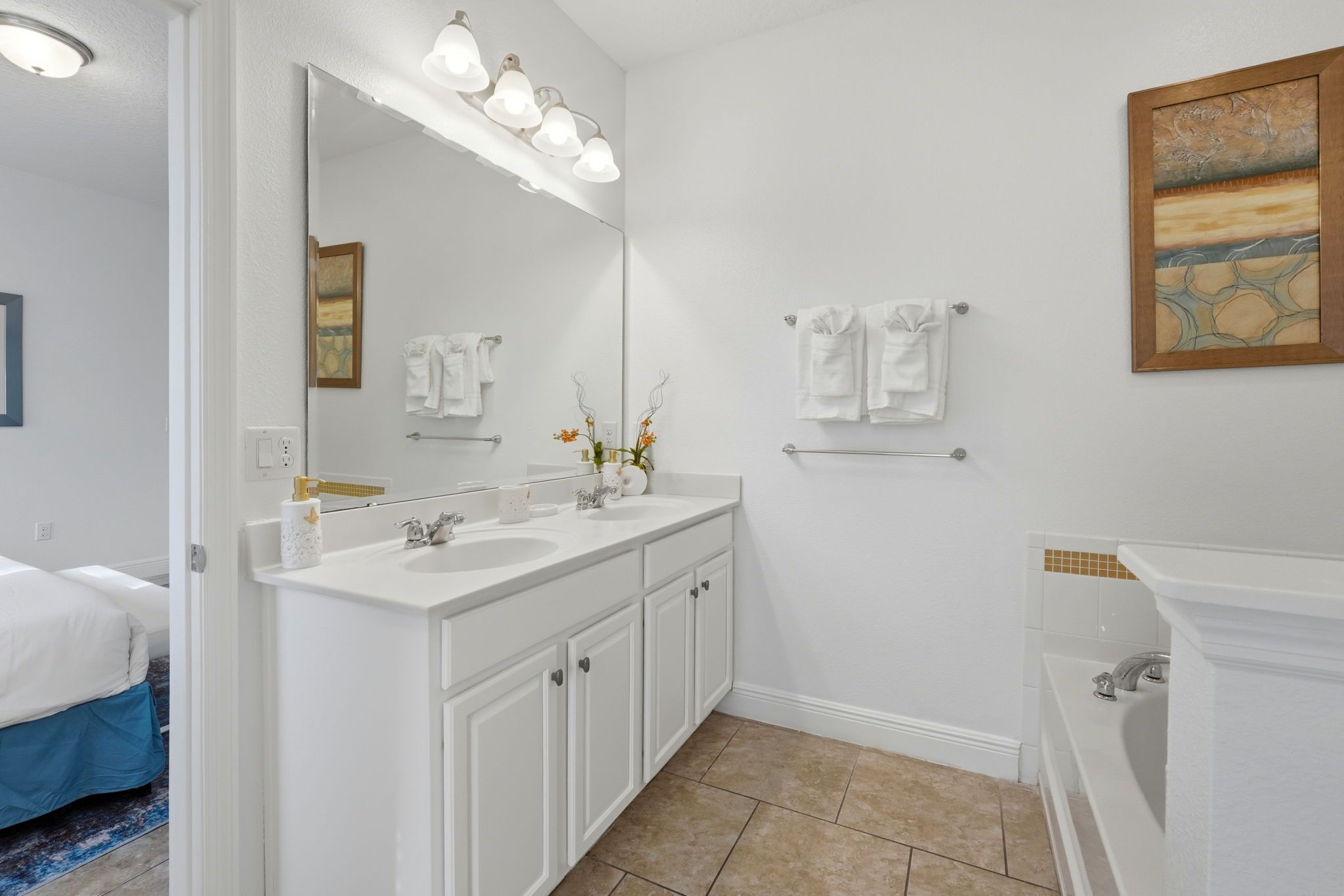 A modern bathroom with a large mirror, two sinks, and a bathtub.