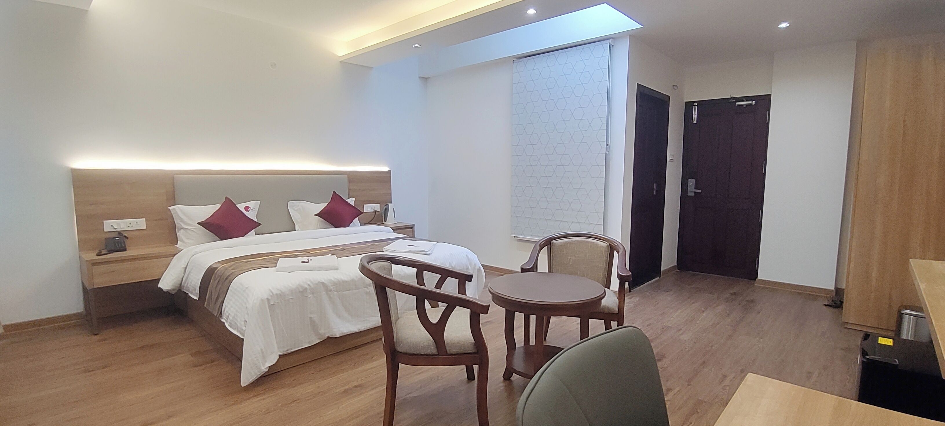 A hotel room with a bed, bedside tables, a desk, and a chair.