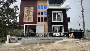 A modern two-story building with a mix of dark and light facades, large windows, and a gated entrance. - Spring Valley Enclave (Kodaikanal)