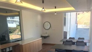 A modern meeting room with a long table and blue chairs, a small sink, and pendant lighting. - Spring Valley Enclave (Kodaikanal)