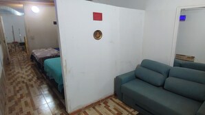 A room with a green sofa, a bed with a teal bedspread, and a patterned floor. - Starlink apartment, furnished, 4 to 6 persons, commercial area (Puerto Iguazú)